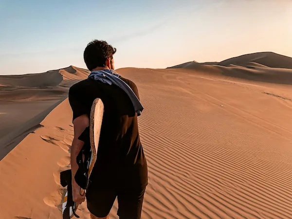 traveler-arriving-sandboarding-dunes-huacachina